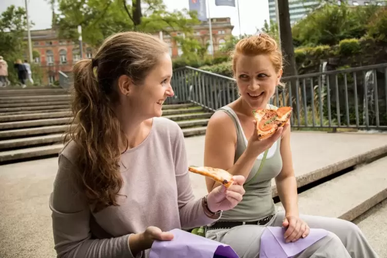 Zwei Frauen essen Pizza im Freien