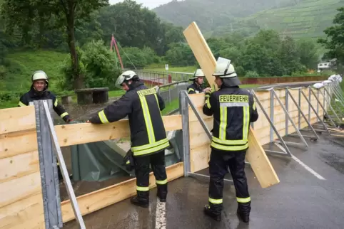 Feuerwehrleute errichten im Ahrtal bei Mayschoss eine Sperrwand aus Holz. 