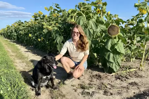 Christina Schuch mit Hündin Paula auf ihrem Feld im Ruchheimer Norden. Die Sonnenblumen dienen als Windbrecher.