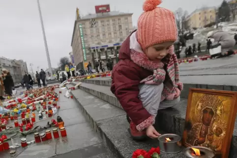 Ein kleines Mädchen zündet in Kiew Kerzen für die Opfer des Kriegs an.