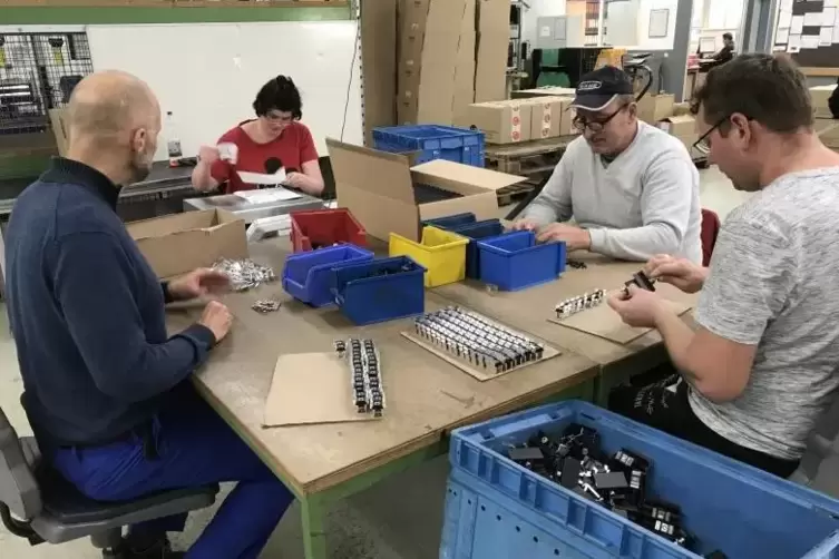  RBG-Mitarbeiter stecken und schrauben Halterungen aus Metall zusammen. Mit ihnen werden Solaranlagen auf D&auml;chern fixiert. 