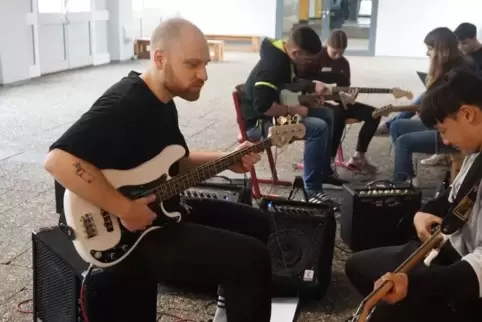 Konzentriert am Bass: Coaches und Schüler, die beim Workshop „Meet The Band" in der Aula die Melodie zu einem Song von Max Giesi