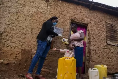 Eine Beamtin übergibt einer Familie in Ruanda Hilfsgüter.