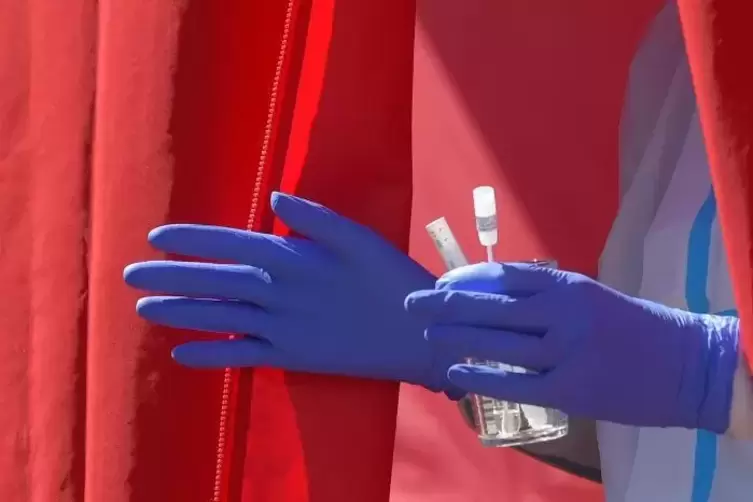 Ein medizinischer Mitarbeiter hält ein Glas mit Test-Pipetten in der Hand.