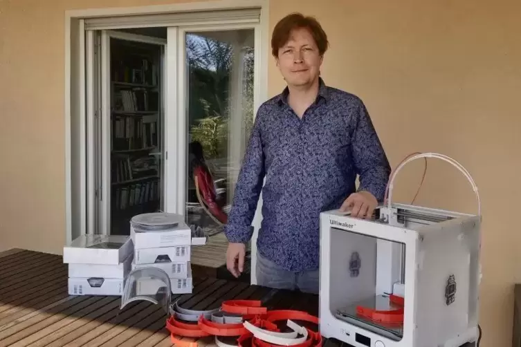 Andreas Eger mit den Maskenhaltern, die er mit dem 3D-Drucker herstellt. Links von ihm liegen die Rollen mit Kunststoff, mit den