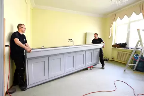 Herein mit dem Teil: Glenn Hull und Markus Grün (von links) rollen die Theke in die neue Lindenstraße.
