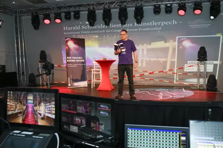 Autor Harald Schneider steht und liest alleine auf der Bühne. Die Soundeffekte zu seiner Lesung – digitale Klospülung und ein ei