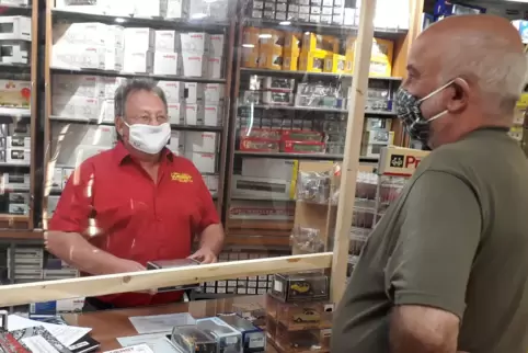 Nicht nur der Kunde, sondern auch Bernhard Werst (links) steht mit Mundschutz am Verkaufstresen.