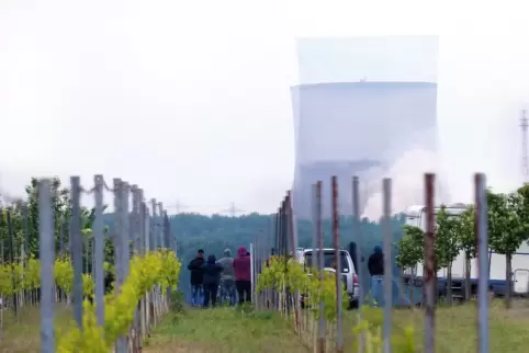 Fällt in sich zusammen: der zweite Kühlturm. Auf dem Feldweg stehen Menschen und beobachten das Spektakel. 