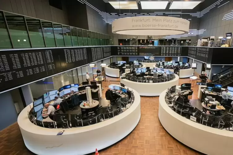  Aktienhändler sitzen auf dem Parkett der Frankfurter Börse an ihren Arbeitsplätzen.