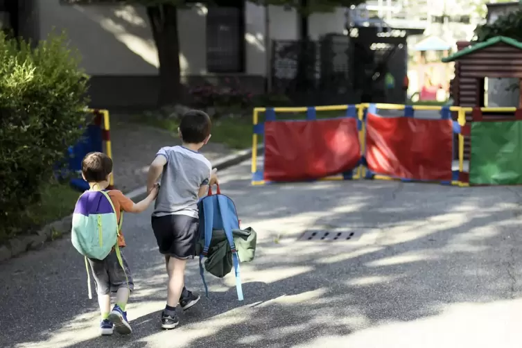 Zwei Kindergartenkinder gehen auf den Eingang eines Kindergartens zu.