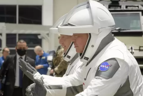 Die NASA-Astronauten Douglas Hurley (links) und Robert Behnken, in SpaceX-Raumanzügen, umarmen ihre Familien virtuell, während s