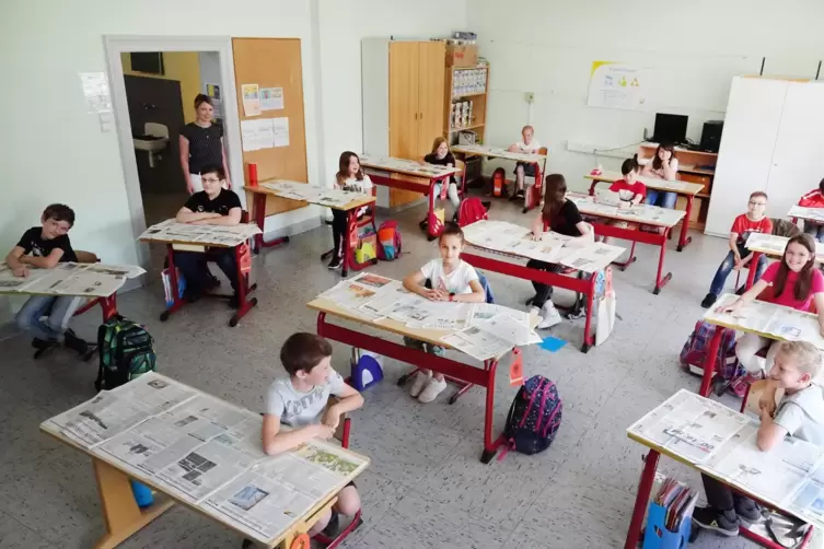 Die Schülerinnen und Schüler der Rodenbacher Grundschulklasse bei der Lektüre der RHEINPFALZ. An der Tür: ihre Klassenlehrerin C