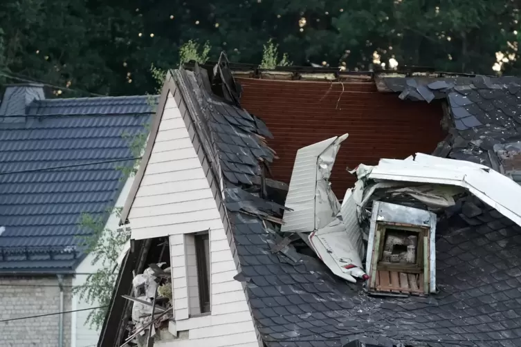 Wrackteile eines Kleinflugzeuges ragen aus dem Dach des Wohnhauses. 