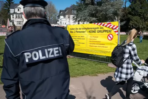 Ein Polizist steht vor einem der Plakate, die die Stadt Saarbrücken aufgestellt hat, auf denen die Verhaltensregeln für den Aufe