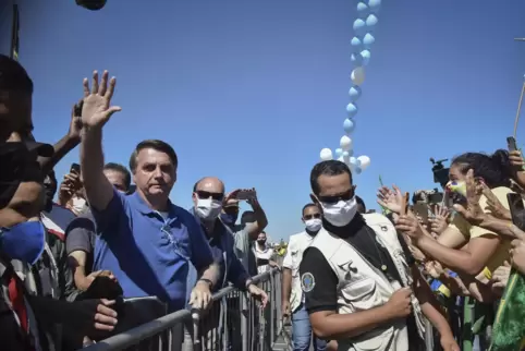 Jair Bolsonaro (links), der Schutzmaßnahmen ablehnt, winkt den vor dem Präsidentenpalast versammelten Anhängern zu.