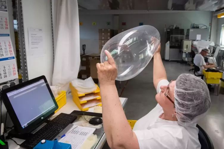 Qualitätskontrolle bei der CPR GmbH in Sarstedt, Niedersachsen: Eine Mitarbeiterin prüft ein frisch produziertes Kondom. Während