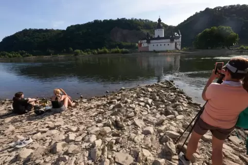 Touristen betrachten die Zollburg Pfalzgrafenstein von einer Landzunge aus. Aufgrund der Trockenheit sinken am Rhein die Pegelst