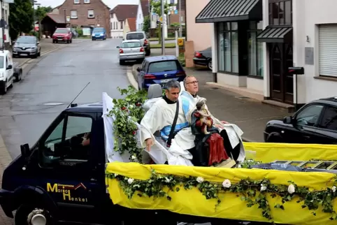 Pfarrer und Diakon sind angeschnallt und halten die Marienstatue auf der Reise gut fest.