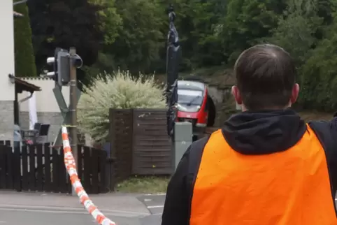 Per Handzeichen und mit Absperrband kontrolliert ein Bahnmitarbeiter derzeit den Übergang bei Imsweiler.