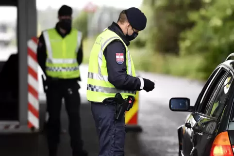 Ein Grenzbeamter kontrolliert an der Grenze einen Autofahrer. 