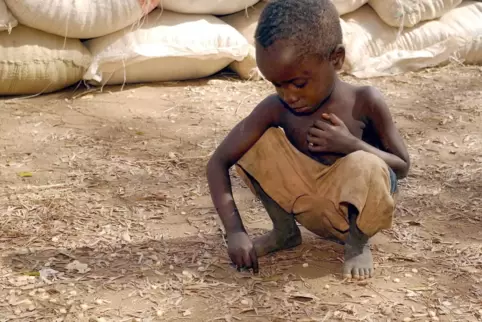 Ein kleiner Junge sammelt in Chimwanza im Süden von Malawi bei einer Lebensmittelverteilung Maiskörner auf.