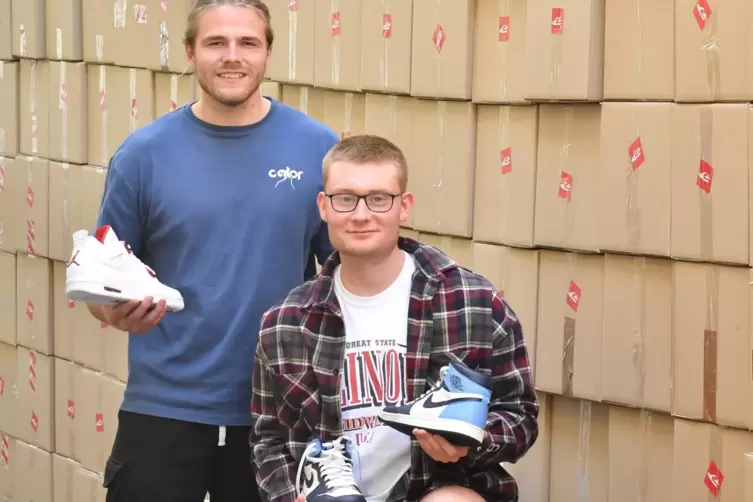 Anton Gartner (links) und Henning Staudt vor einer „Wand“ aus rund 200 Kartons mit selbstdesignten „Sneakertaschen“. Diese haben