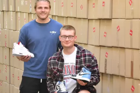 Anton Gartner (links) und Henning Staudt vor einer „Wand“ aus rund 200 Kartons mit selbstdesignten „Sneakertaschen“. Diese haben