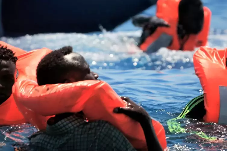 Migranten treiben mit Rettungswesten im Mittelmeer. 