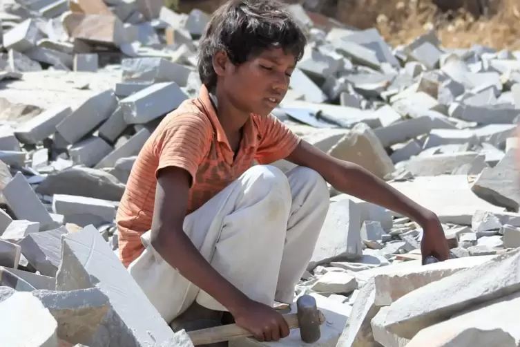 Ein kleiner Junge bearbeitet in der indischen Provinz Rajasthan mit einem Hammer Marmorsteine. 