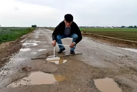 Udo Bentz untersucht die Schlaglochpfützen auf dem Rad- und Wirtschaftsweg zwischen Lambsheim und Heßheim.