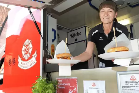 Guten Appetit: Diana Haust reicht Burger aus dem umgebauten Feuerwehr-Fahrzeug. 