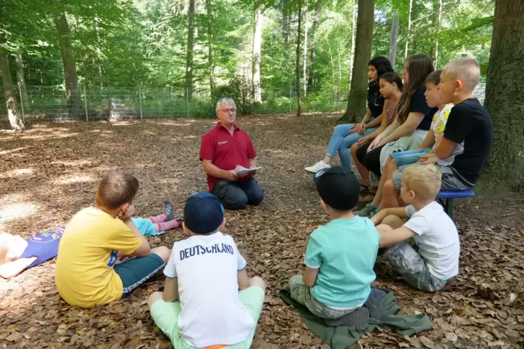 Keine Märchenstunde: Förster Volker Westermann (rotes Shirt) liest den jungen Teilnehmern des Ferienprogramms in der Walderholun