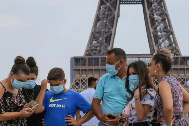 Eine italienische Familie mit Mund-Nasen-Schutz am Eiffelturm. 