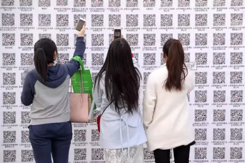 Arbeitsplatzsuche auf chinesisch: Junge Frauen scannen auf einer Messe in Schanghai mit der App Wechat QR-Codes, hinter denen si
