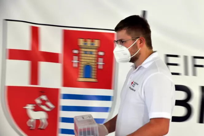 Ein Helfer des Deutschen Roten Kreuzes bringt in der Teststation Bitburg Proberöhrchen, die für Tests auf das Coronavirus benöti Ein Helfer des Deutschen Roten Kreuzes bringt in der Teststation Bitburg Proberöhrchen, die für Tests auf das Coronavirus benöti
