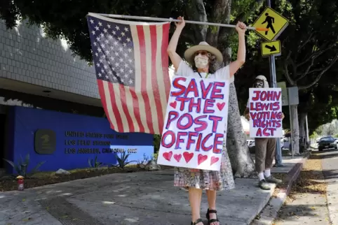 Hat die Regierung die Post kaputtgespart? Erica Koesler (links) und David Haerle aus Los Angeles demonstrieren vor einem Postamt