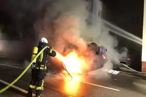 Sonntagnacht in Lingenfeld: Ein Feuerwehrmann löscht das brennende Fahrzeug, das sich überschlagen hatte. 