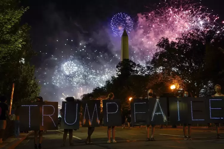 Trump ist gescheitert, schreiben diese Aktivisten in die Nacht. Dahinter &uuml;berstrahlt sie ein Feuerwerk, das die Republikaner f&uuml;r