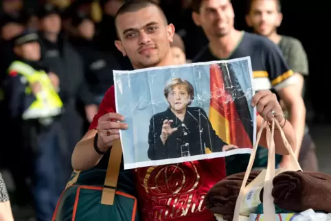 München, Anfang September 2015: Ein frisch angekommener Flüchtling hält auf dem Bahnsteig ein Foto von Angela Merkel in den Händ