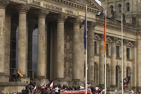 Teilnehmer einer Kundgebung gegen die Corona-Maßnahmen stehen vor dem Reichstag.