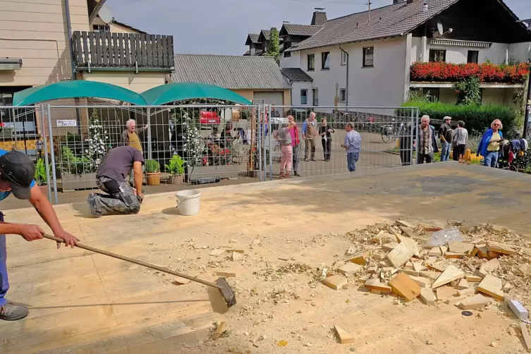 Handwerker s&auml;ubern nach dem Kran-Einsatz die Holzb&uuml;hne. 