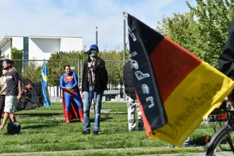 Demonstranten stehen im Berliner Regierungsviertel vor einem Bundestagsgebäude und demonstrieren gegen die Maßnahmen zur Eindämm