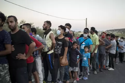Migranten stehen in der Nähe des ausgebrannten Flüchtlingslagers Moria auf Lesbos in einer Schlange, um Lebensmittel zu erhalten