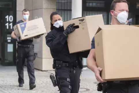 Bundespolizisten tragen bei einer Razzia Kartons mit beschlagnahmten Unterlagen vor einem Bürogebäude in der Region Hannover. 