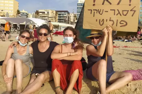 Hedva Yaari (mit Demo-Schild) protestiert wie viele junge Leute am Strand von Tel Aviv gegen Premier Netanjahus Corona-Politik.