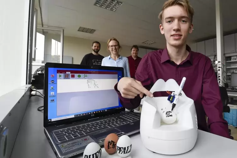 Eine Maschine, mit der man Bilder und Schrift auf Eier übertragen kann, hat KG-Schüler Jan Eichner entwickelt. Mit ihm freuen si
