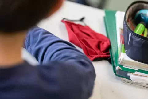 Eine Corona-Alltagsmaske liegt auf einer Schulbank.