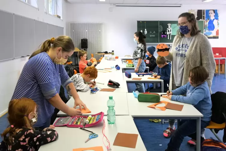 Basteln mit Mund-Nasenschutz: Anna Heck (rechts) zeigt den Kindern, wie es geht. 