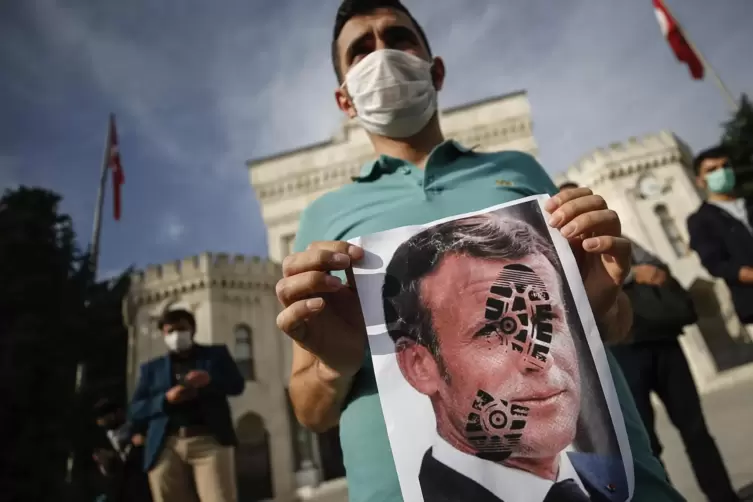Empört in Istanbul: Ein junger Mann hält ein mit einem Schuhabdruck versehenes Foto von Emmanuel Macron, Präsident von Frankreic